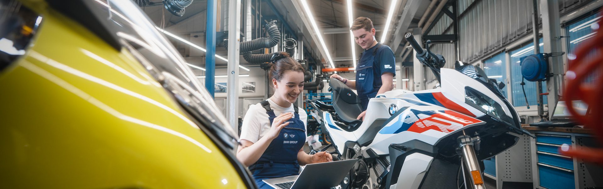 Zwei Azubis bei der BMW Group arbeiten an einem BMW Motorrad in einer Werkstatt.
