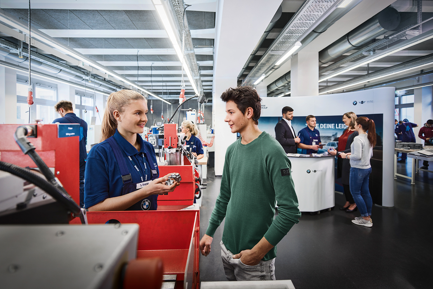 Jugendliche erkunden berufliche Möglichkeiten bei BMW in einer modernen Werkstatt.