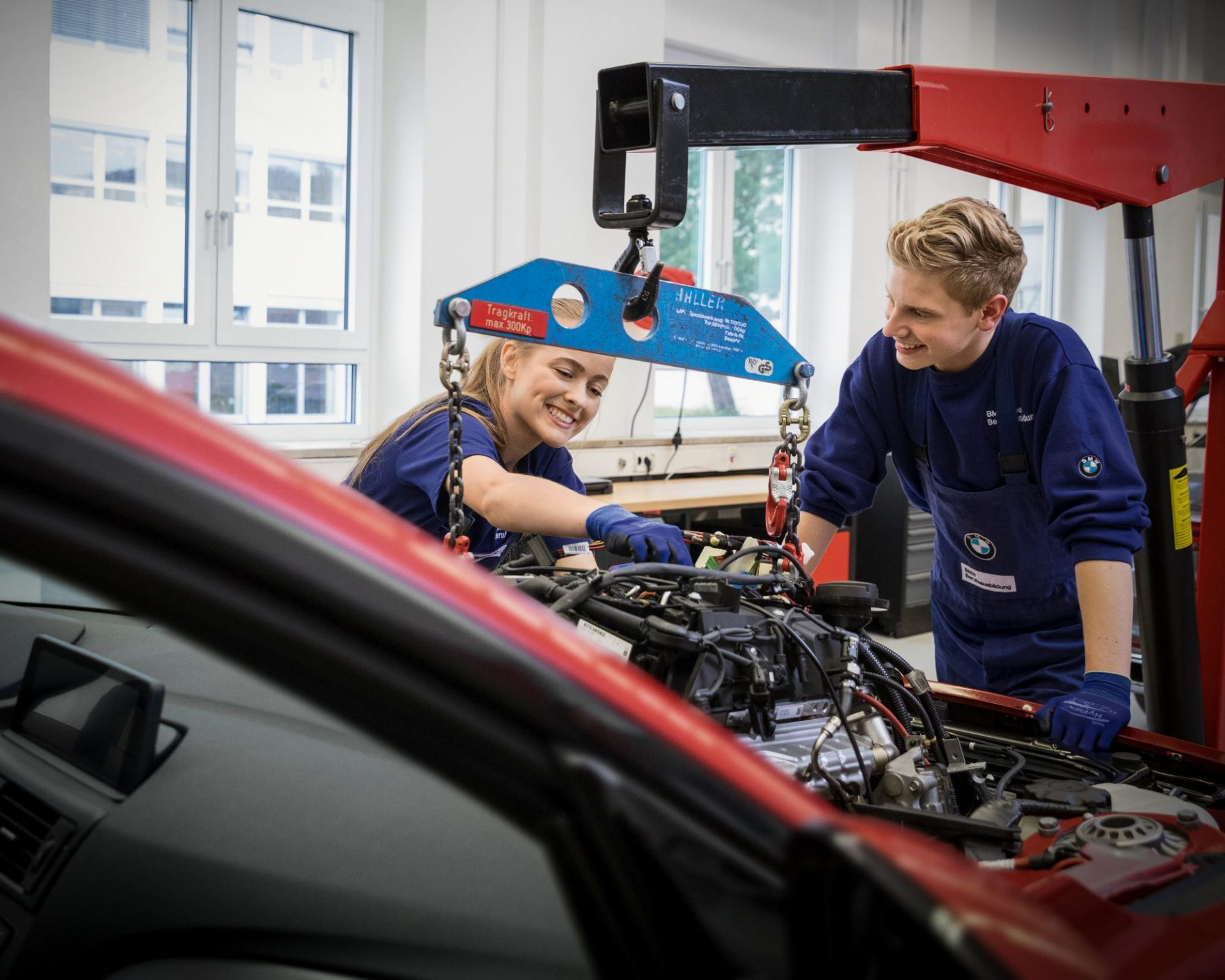 Zwei Azubis im Bereich Kfz-Mechatronik arbeiten am Motor eines Autos