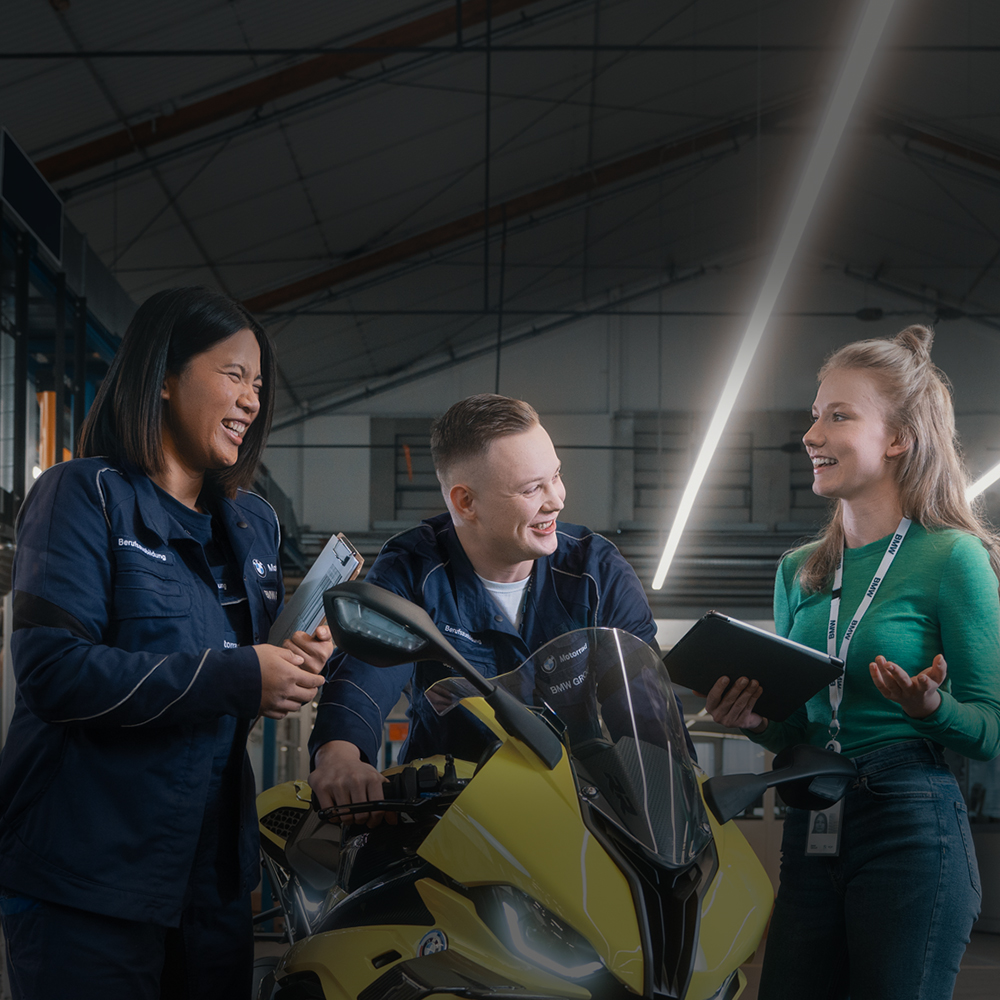 Drei Azubis beschäftigen sich mit einem BMW Motorrad.