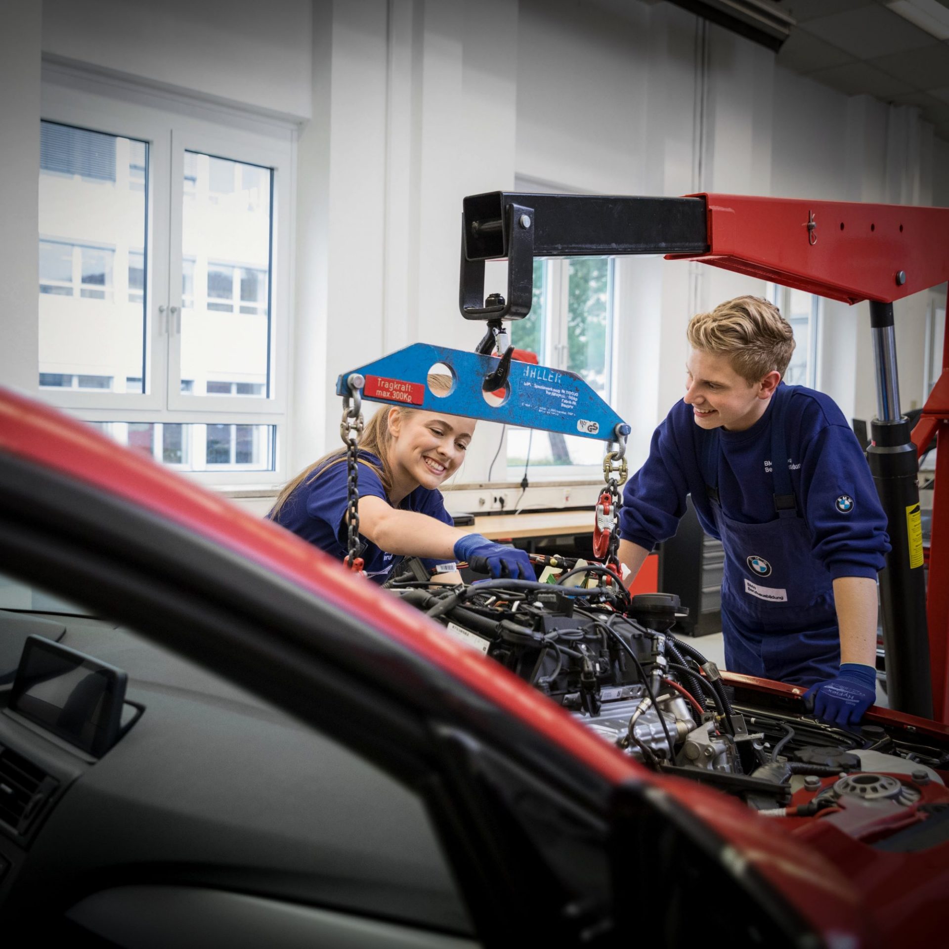 Zwei Azubis im Bereich Kfz-Mechatronik arbeiten am Motor eines Autos
