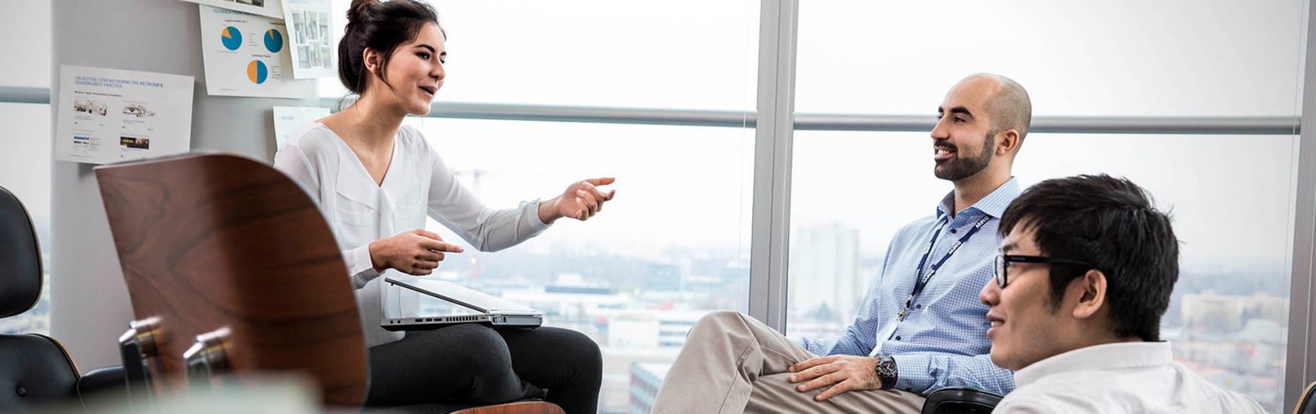 Three employees at the BMW Group are sitting together and having a conversation.