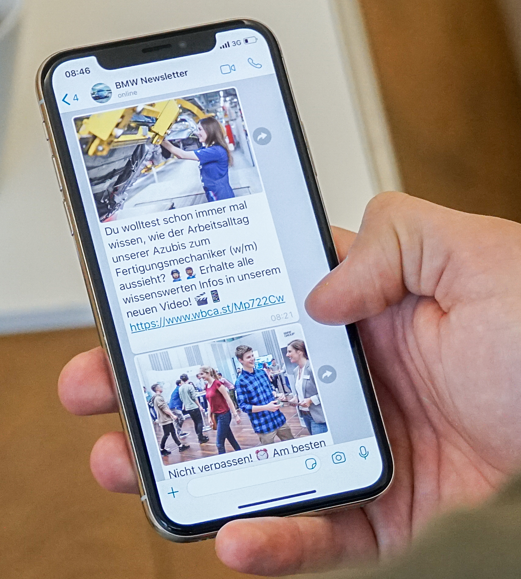Eine Hand, die ein Smartphone hält, auf dem der BMW Schülernewsletter geöffnet ist.