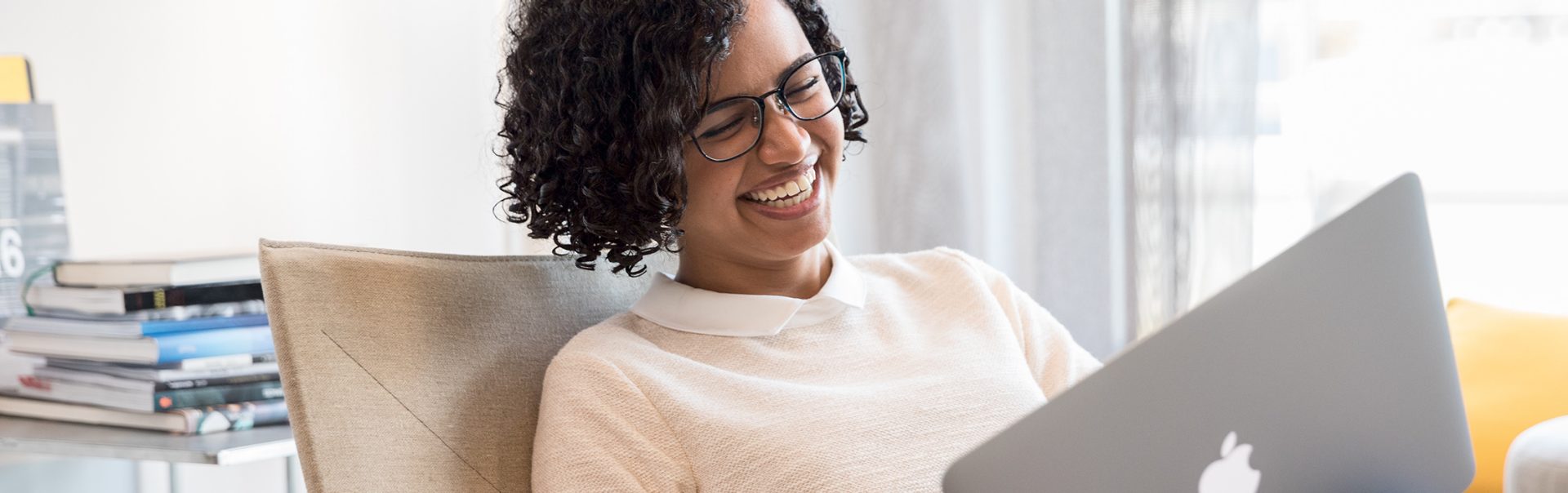 Lachende Frau arbeitet an einem MacBook