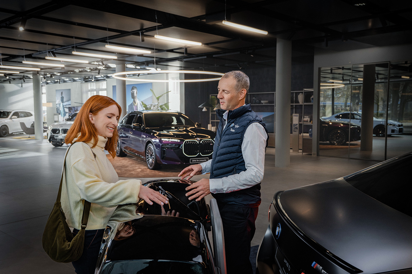 Ein Aftersales-Mitarbeiter erklärt einer Kundin eine Dachbox