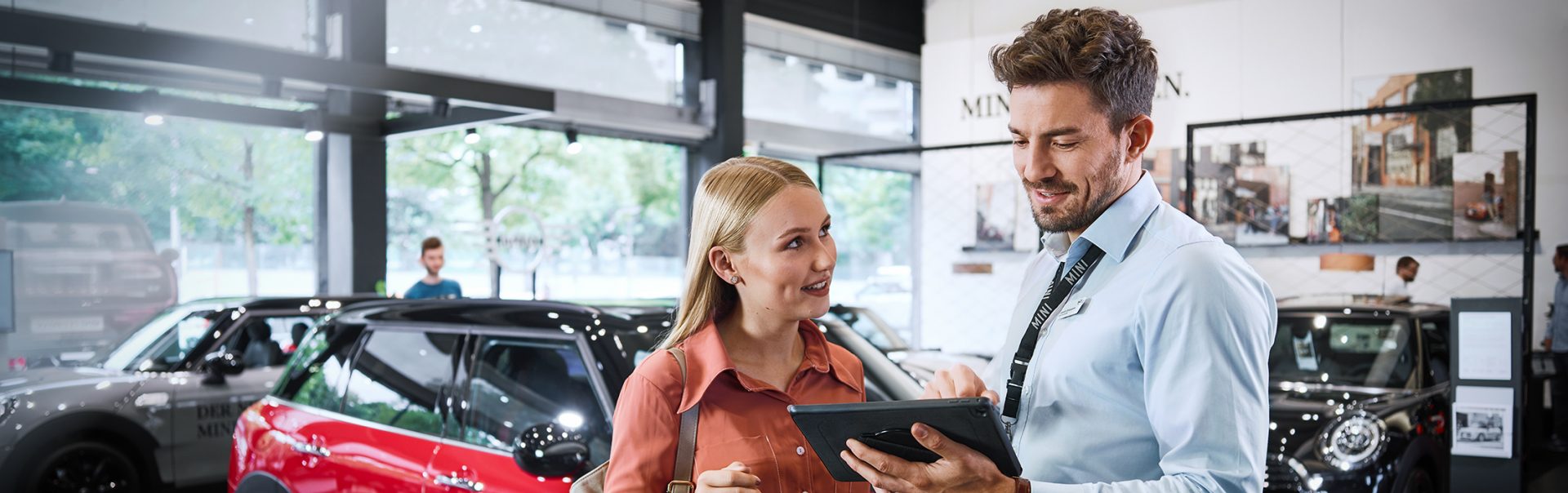 Ein netter Mitarbeiter im Vertrieb führt ein Gespräch mit einer Kundin in einem BMW Autohaus.