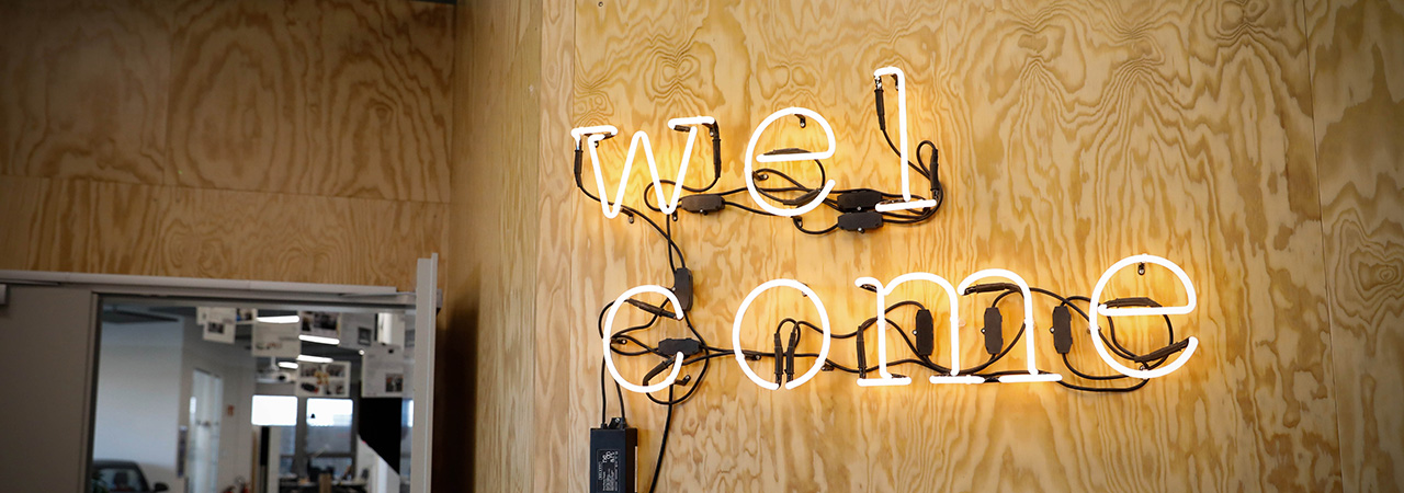 Neonzeichen mit dem Wort 'welcome' an einer Holzwand bei BMW
