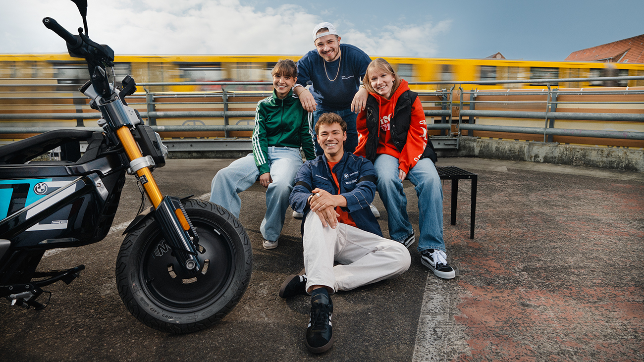 Vier Azubis mit BMW CE02 Scooter und Berliner U-Bahn im Hintergrund