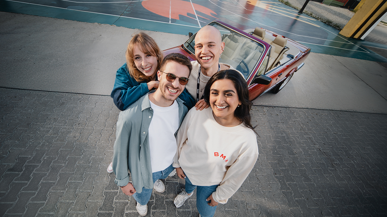 Vier Azubis vor einem alten BMW Cabrio