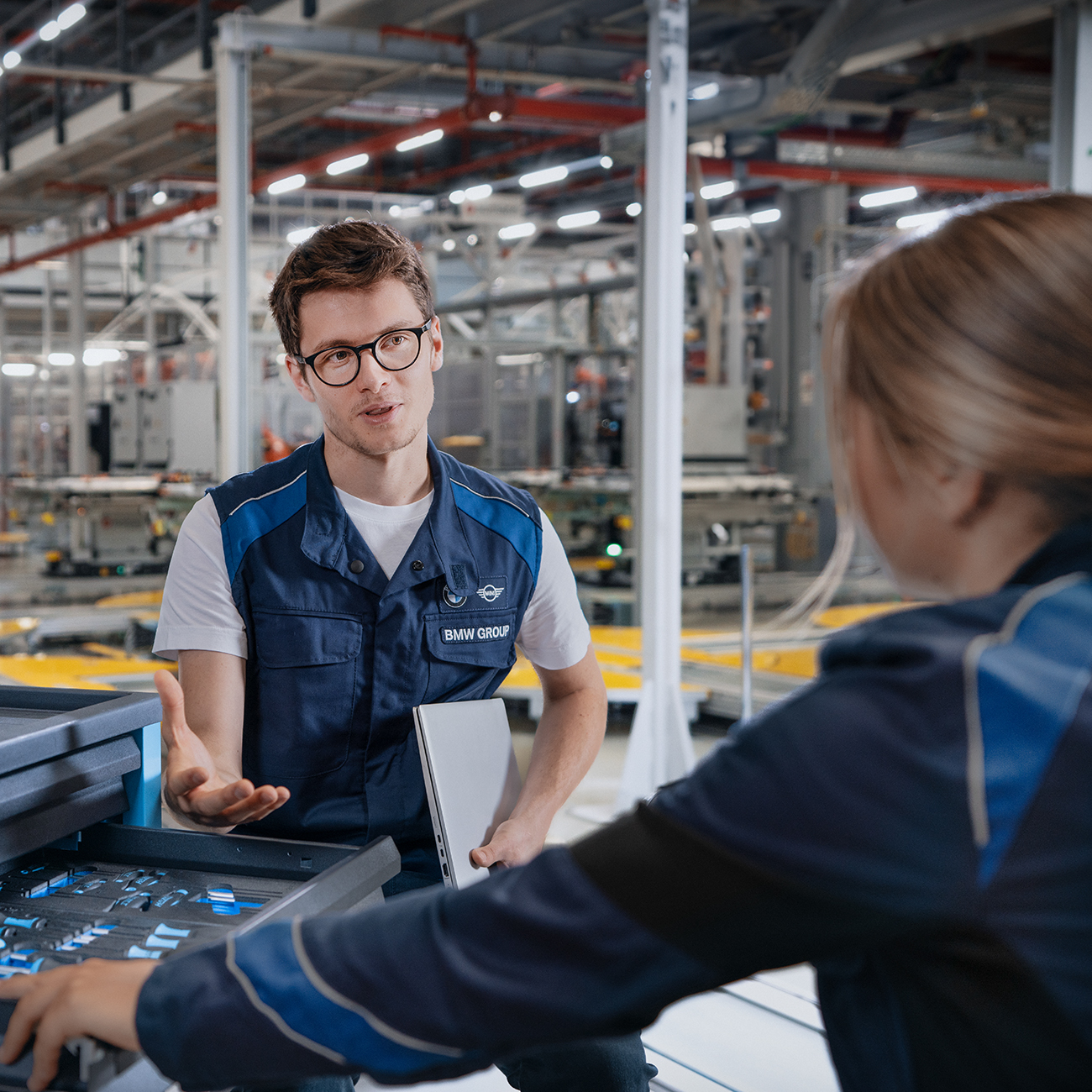 A BMW Group working student in production is having a chat with a colleague.