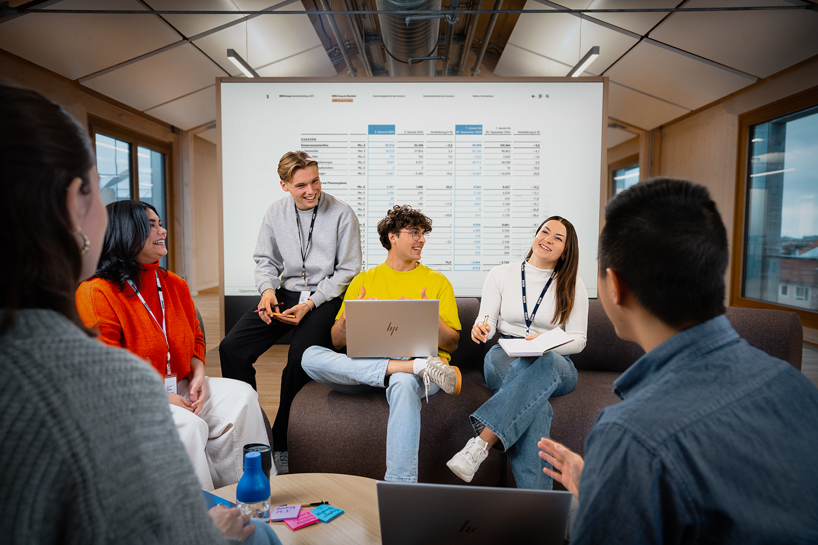 Eine Gruppe Studierender unterhalten sich angeregt in einem modernen Bürosetting