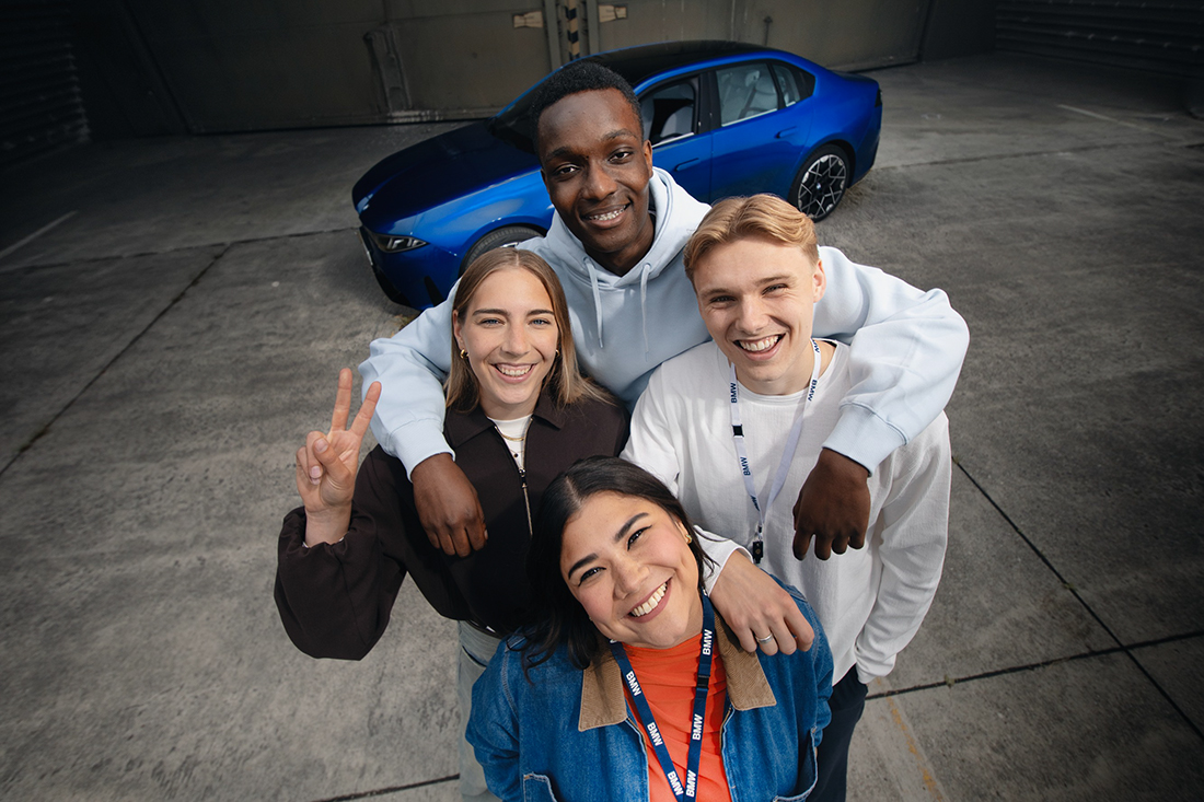 Eine Gruppe Studierender posieren für ein Foto vor einem BMW i3