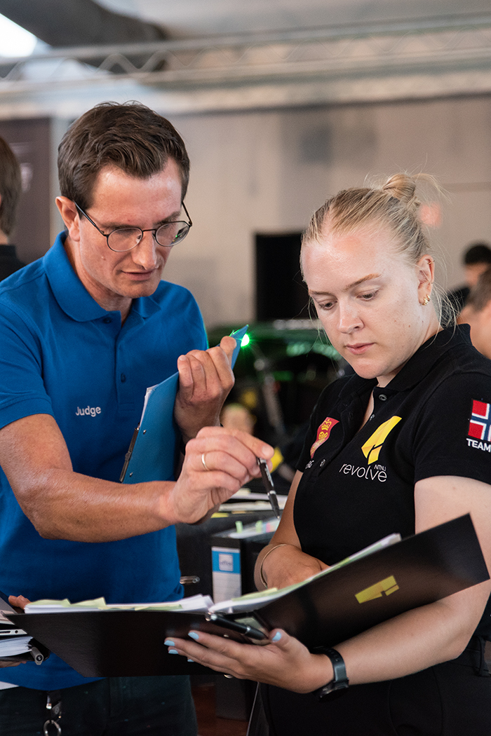 BMW Formula Student Judge geht mit Studentin durch Dokumente.