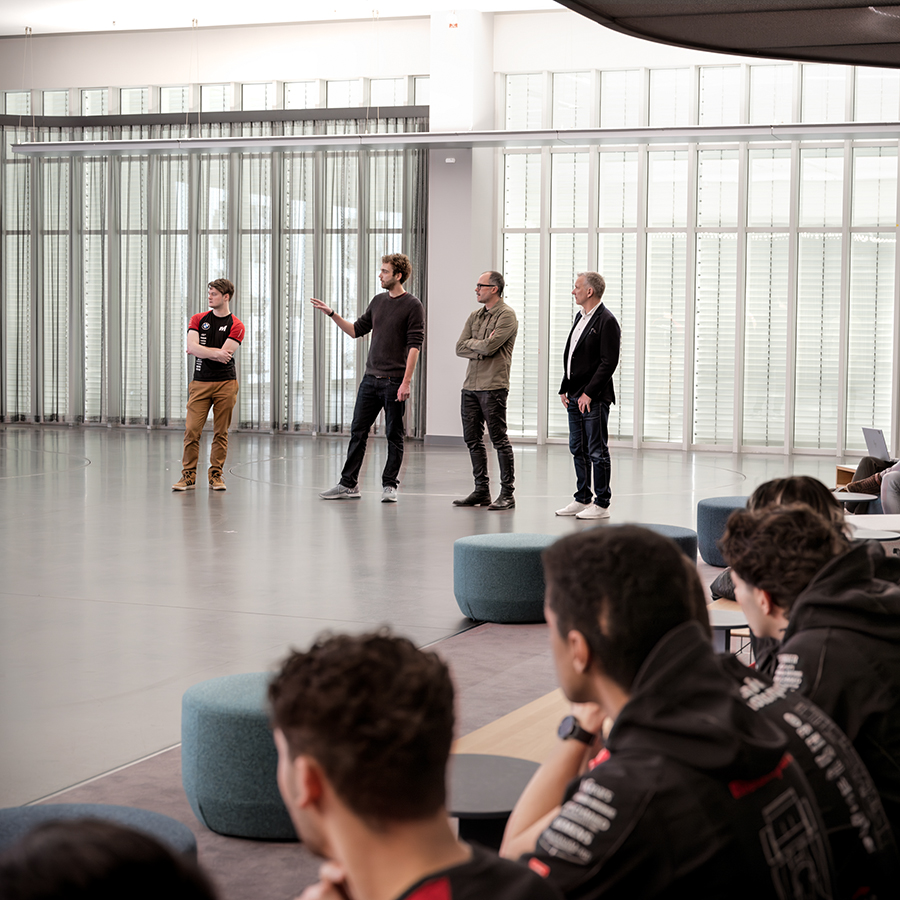 Vier Personen präsentieren vor einer Gruppe an Personen.