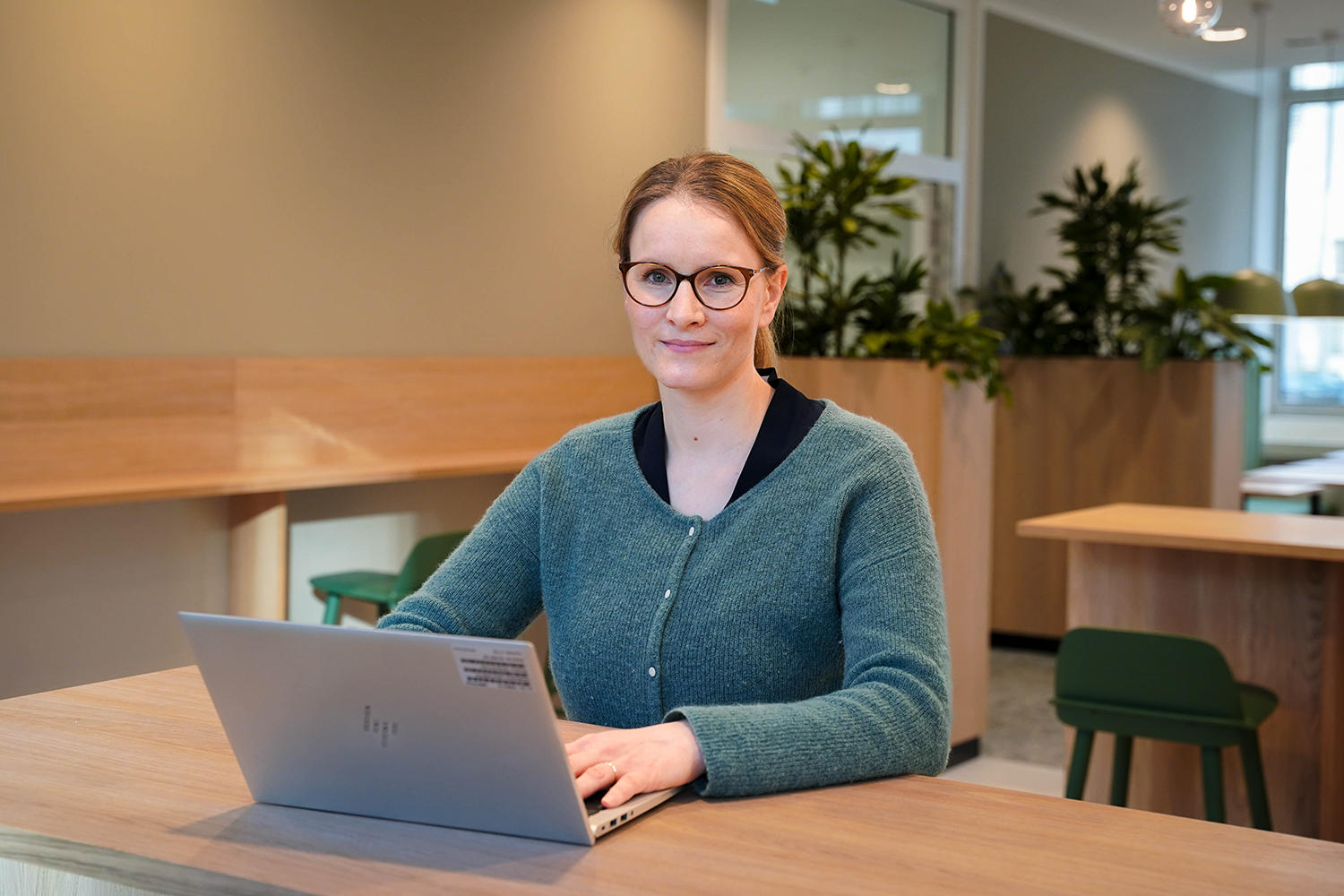 The head of Production Strategy is working on her computer smiling at the camera.