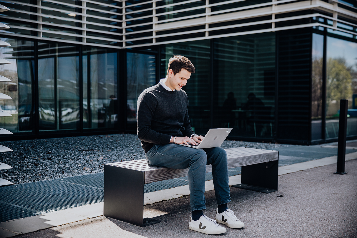 Trainee in IT working outdoors on his computer.