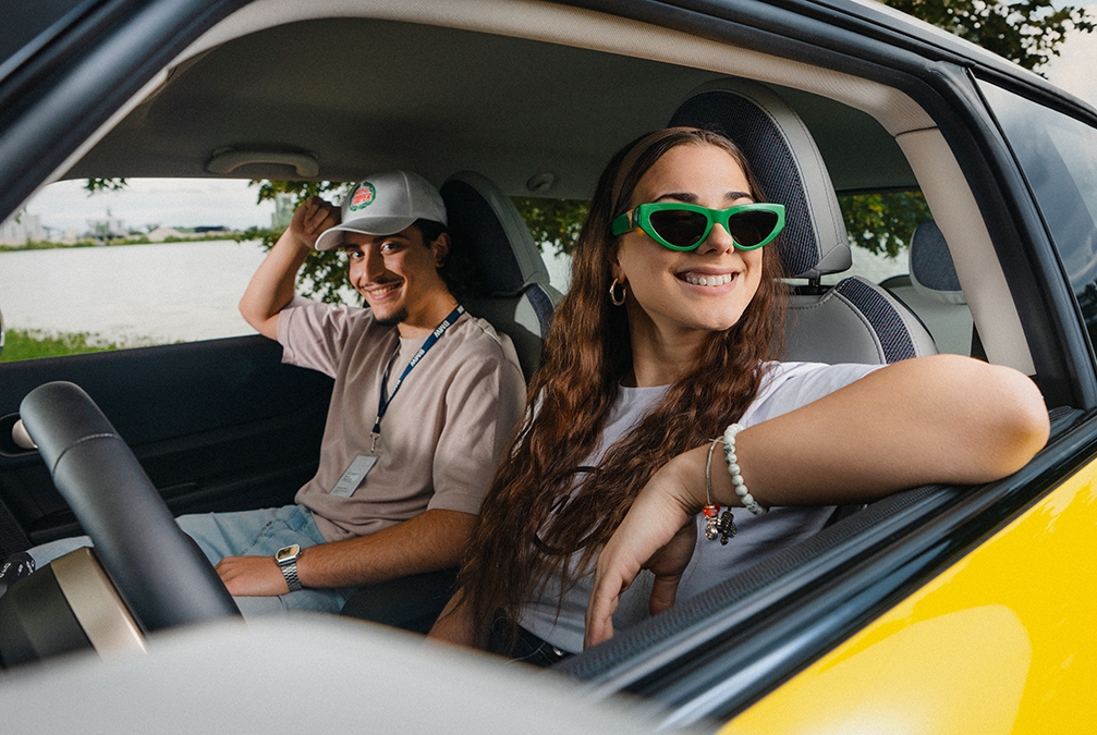 Junge Auszubildende bei BMW genießen eine Autofahrt im Freien mit Sonnenbrillen.