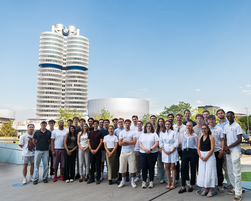 Eine Gruppe Studierender bei einem Gruppenfoto vor dem Vierzylinder Gebäude