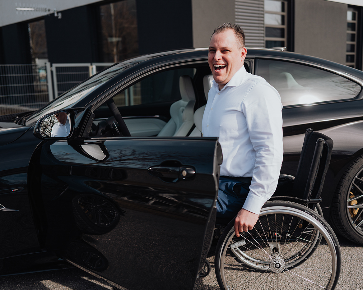 BMW Mitarbeiter Markus mit seinem Rollstuhl vor seinem BMW M4