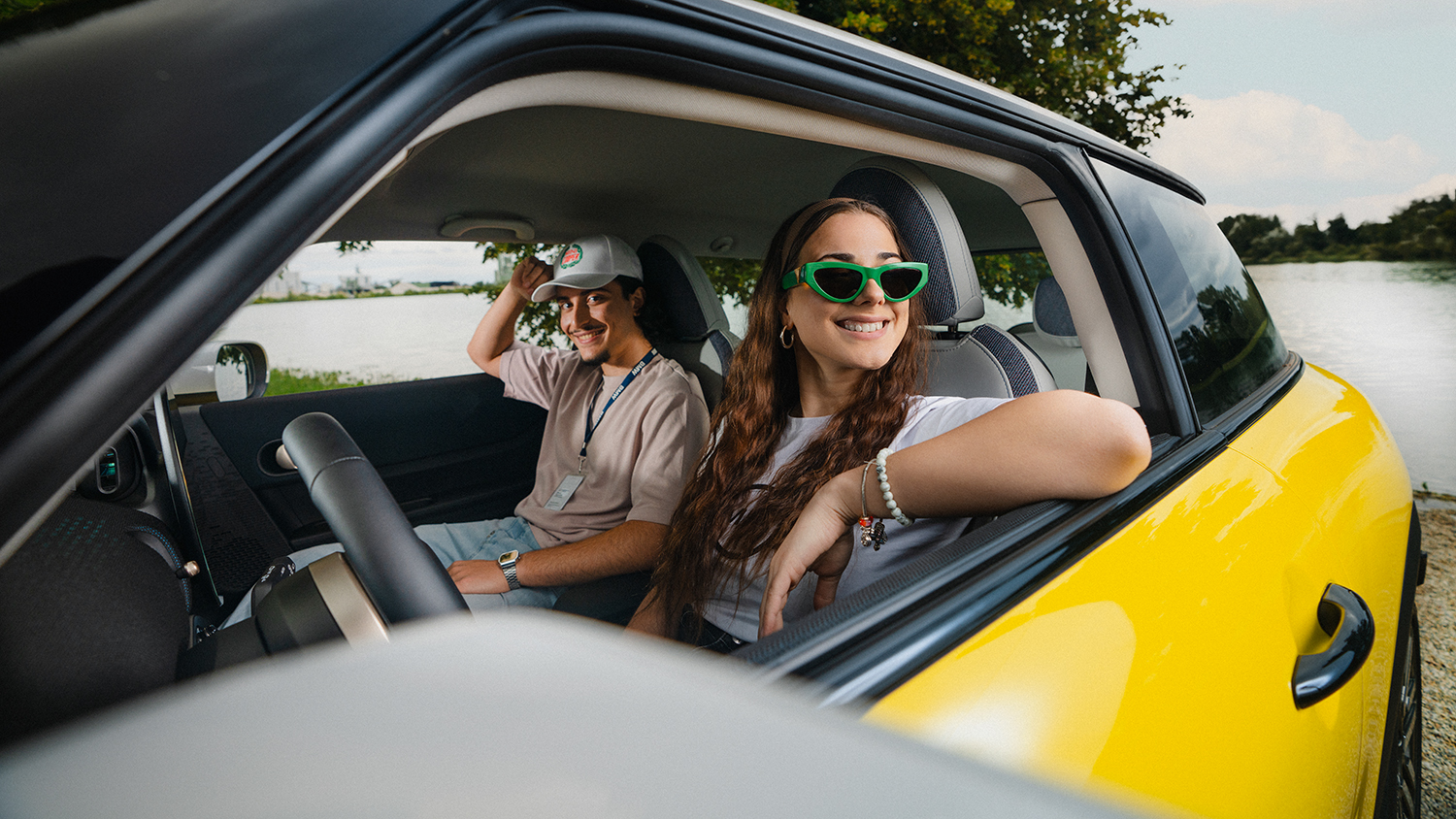 Junge Auszubildende bei BMW genießen eine Autofahrt im Freien mit Sonnenbrillen.