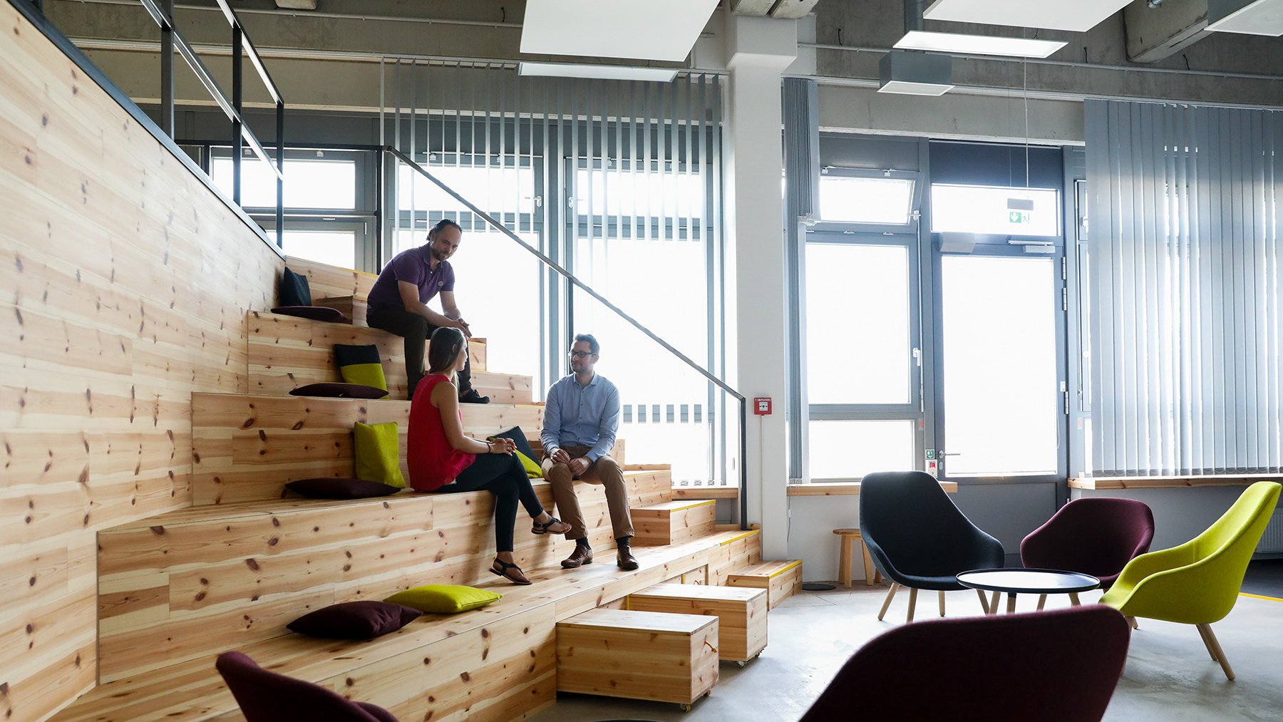 Innovatives Arbeitsumfeld mit Holzstufen, auf denen sich Kollegen unterhalten.