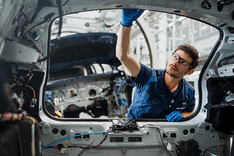 Das Bild zeigt einen Produktionsmitarbeiter bei der Arbeit an einer Karosserie.