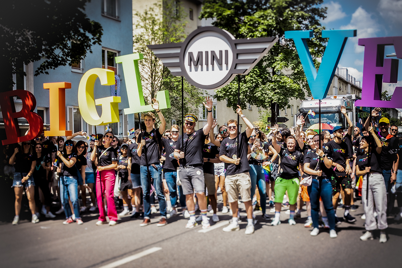 Eine große Personengruppe auf dem Christopher Street Day hält große Buchstaben, die die Wörter "Big Love" ergeben