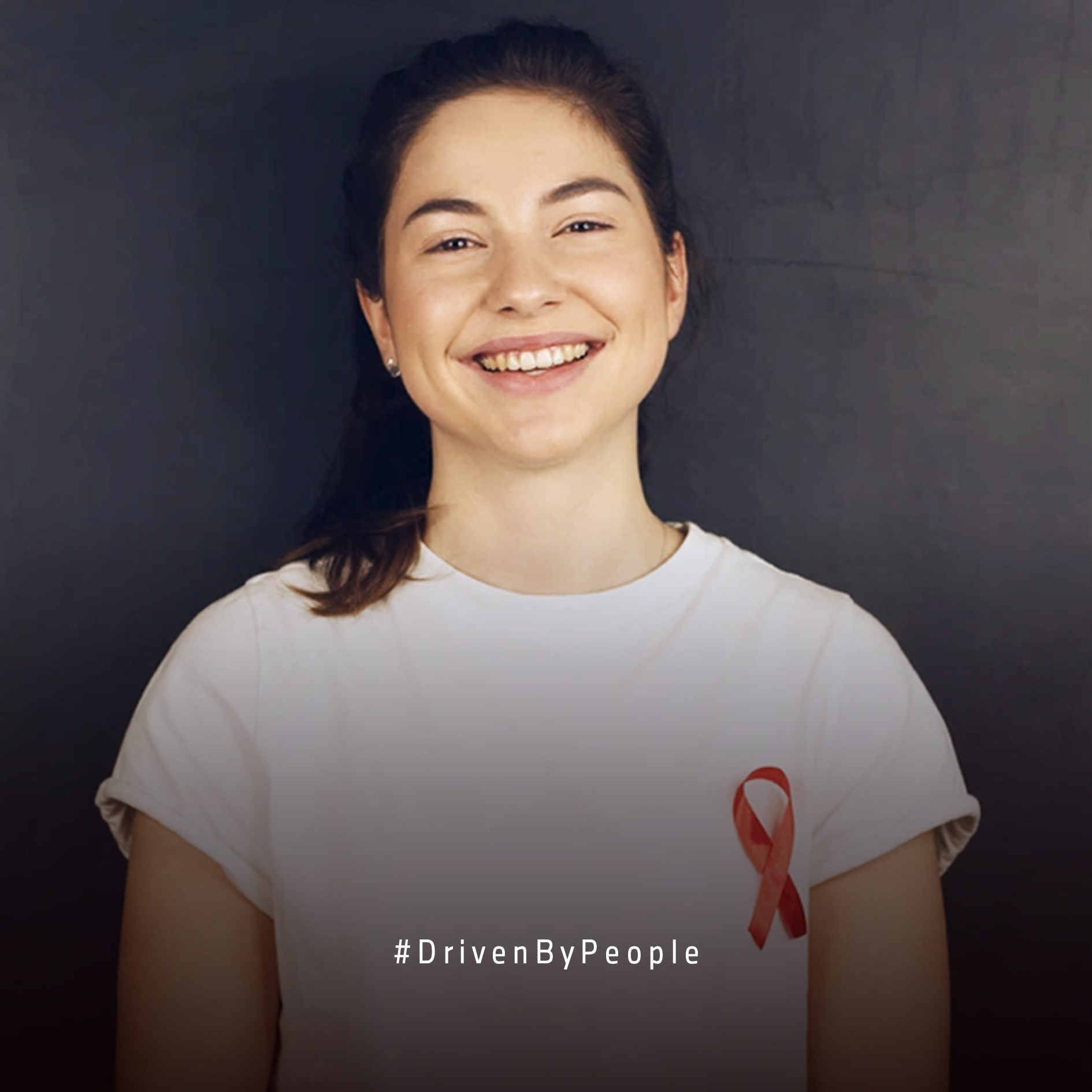 Eine BMW Group Mitarbeiterin, die ein weißes T-Shirt mit der roten HIV Schleife trägt.