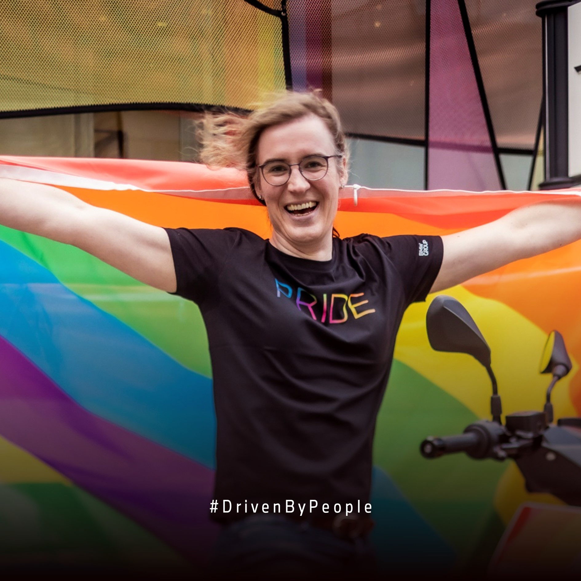 Eine mitarbeitende Person bei der BMW Group mit einer Pride Flagge auf dem Christopher-Street-Day