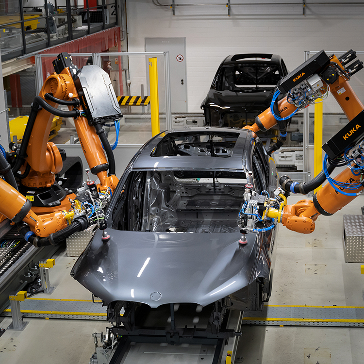 Silver BMW car frame being built by machines. 