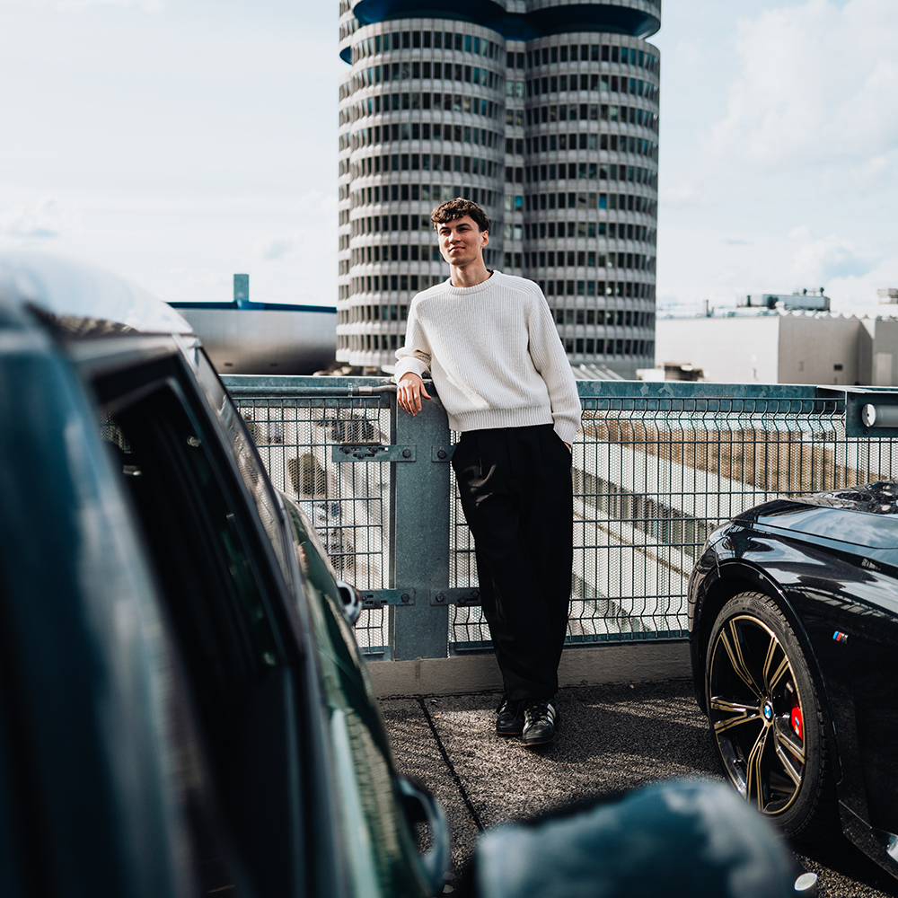 Dualer Student Anton steht auf einem Parkhaus vor dem BMW Vierzylinder