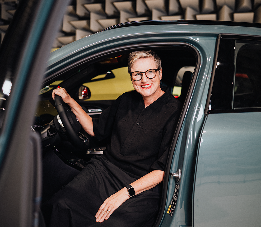 Daniela sitzt auf dem Fahrersitz eines BMW iX2 und lächelt in die Kamera.