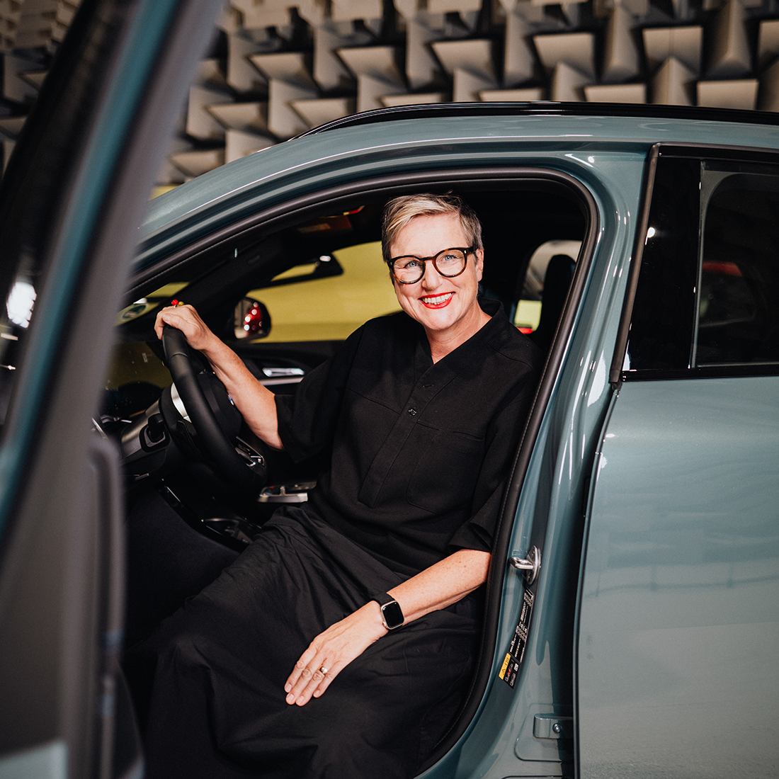 Daniela sitzt auf dem Fahrersitz eines BMW iX2 und lächelt in die Kamera.