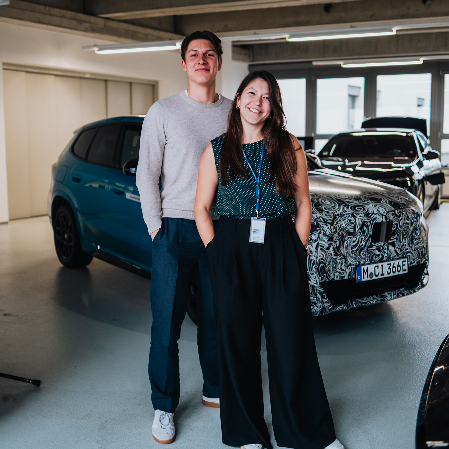 Dominique und Arne stehen mit Händen in den Taschen vor dem BMW IX2.