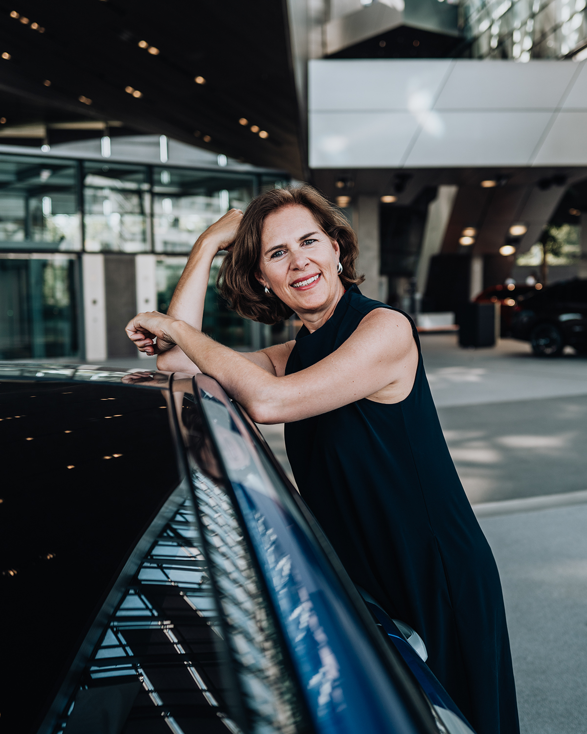 Mitarbeiterin bei der BMW Group lehnt an einem BMW M8.