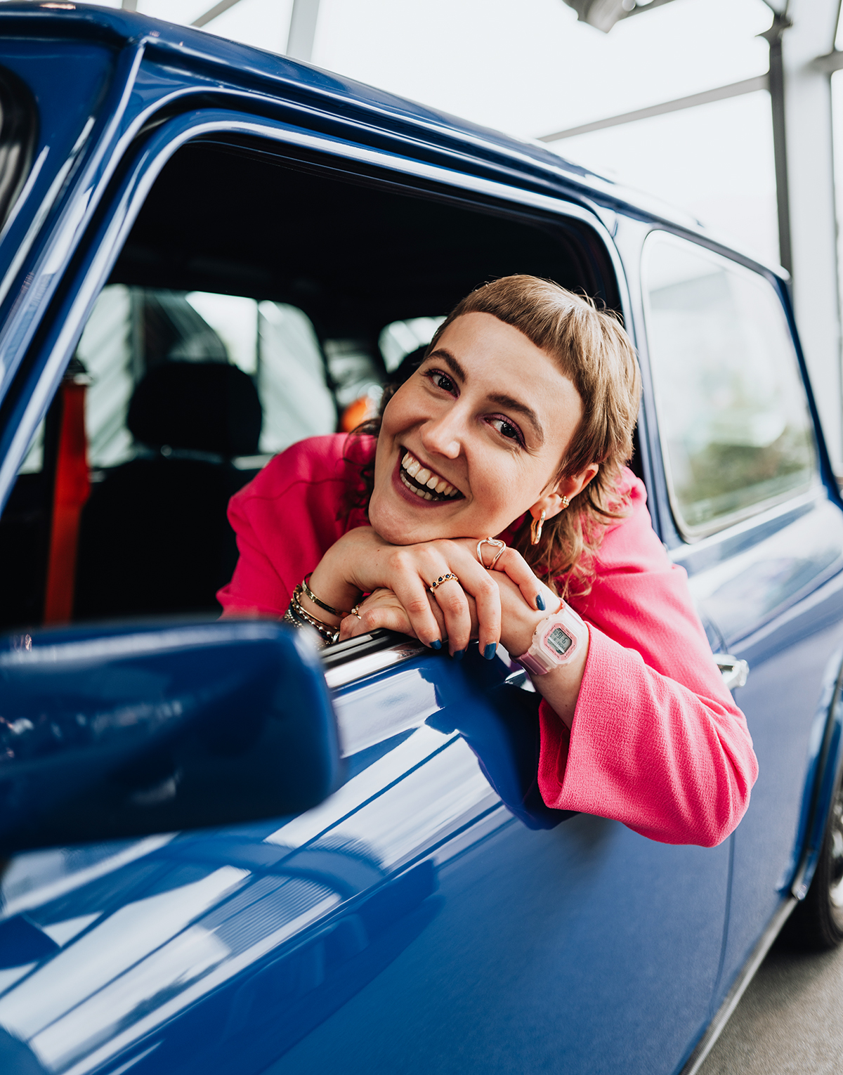 Die Praktikantin lehnt sich aus dem Fenster im Oldtimer-MINI