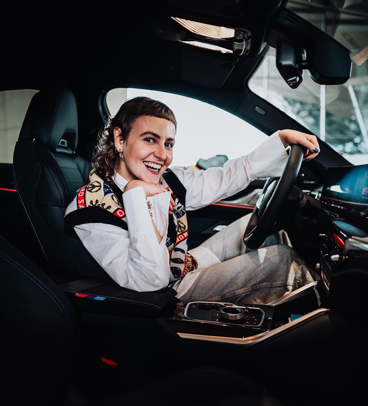 Die Praktikantin sitzt auf dem Fahrersitz eines BMW M3.