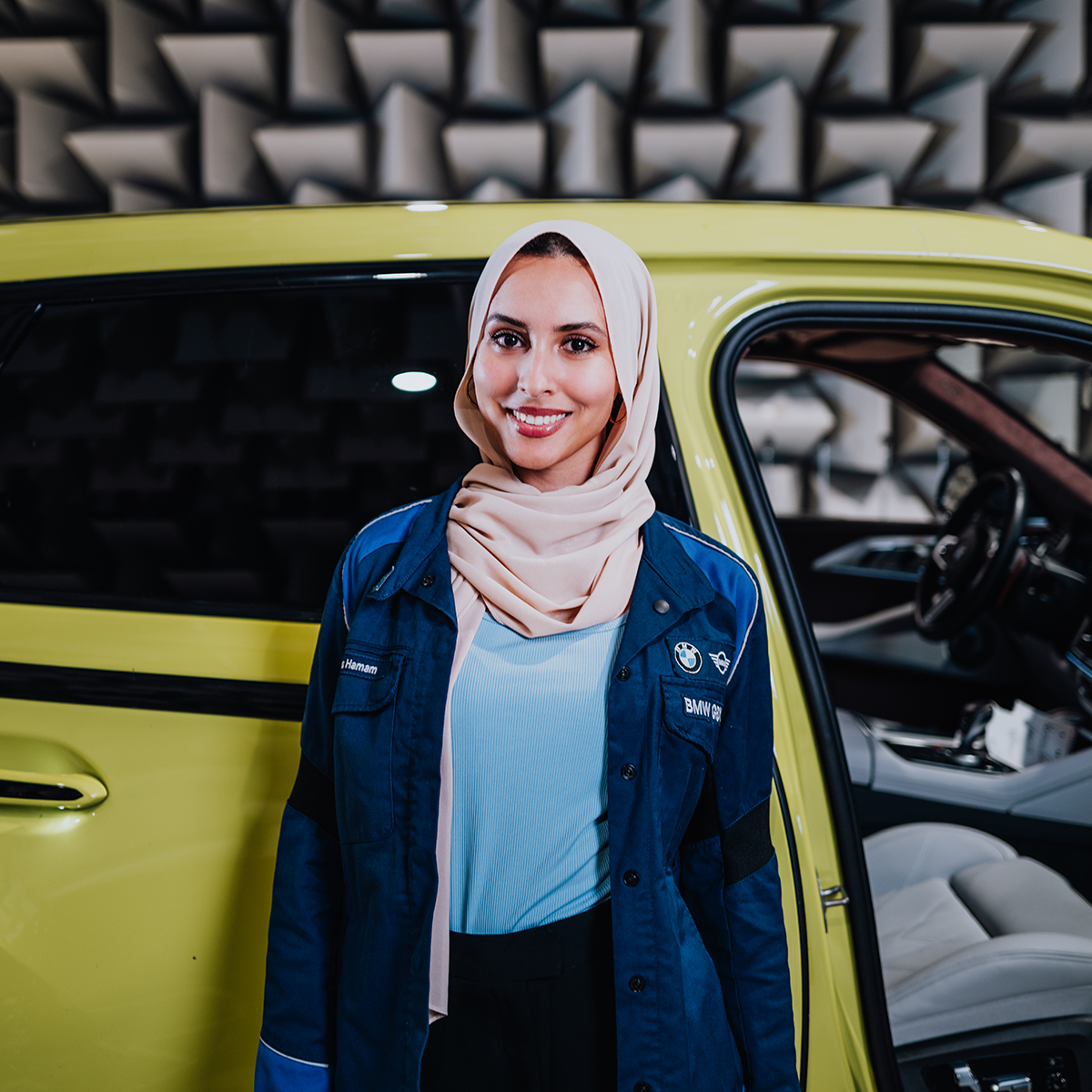 Ines lächelt in die Kamera vor der Tür eines BMW XM.