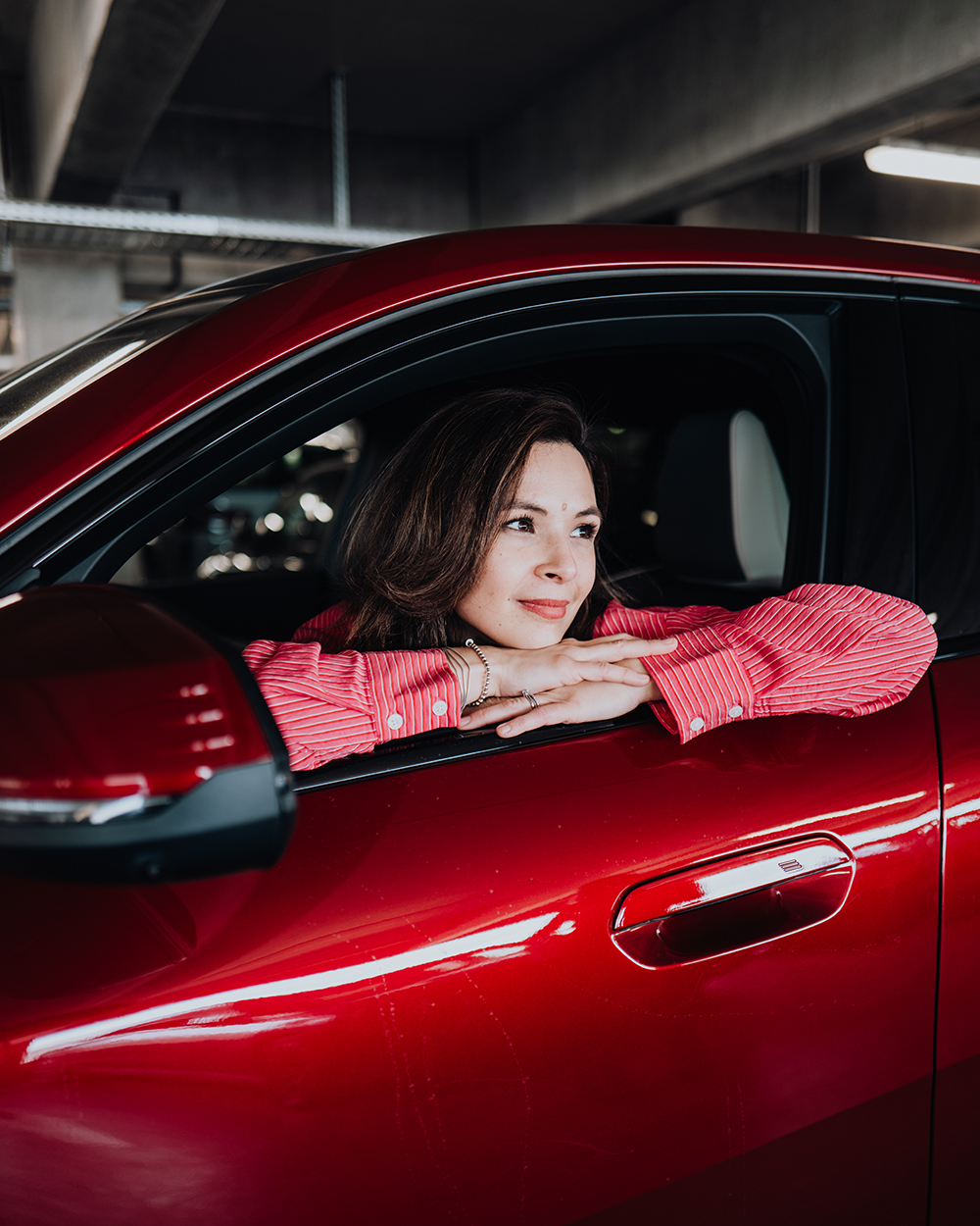 BMW Mitarbeiterin Denise schaut aus dem Fenster eines roten BMW X2