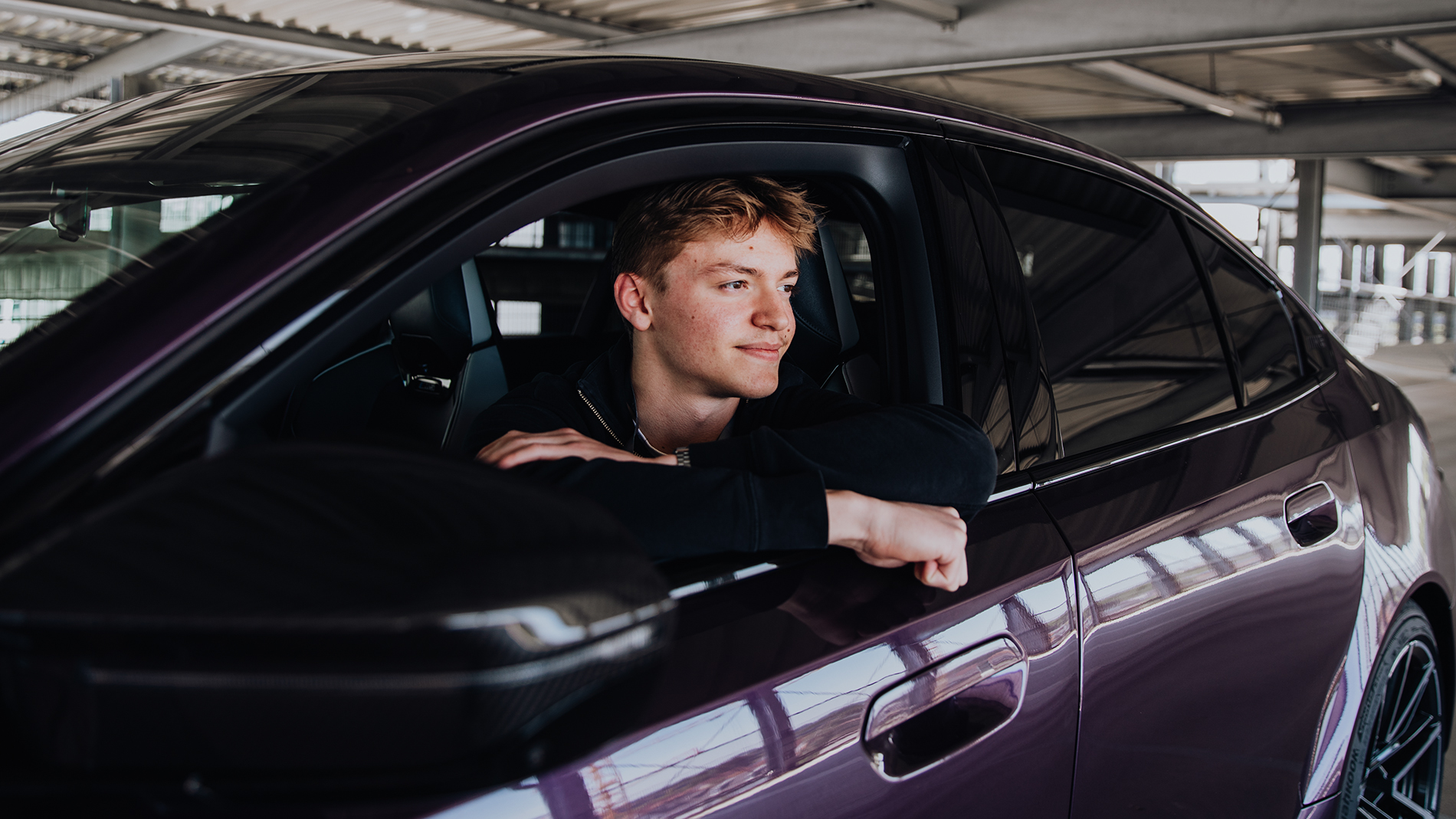 Azubi Tobias schaut aus dem Fahrerfenster eines BMW M5