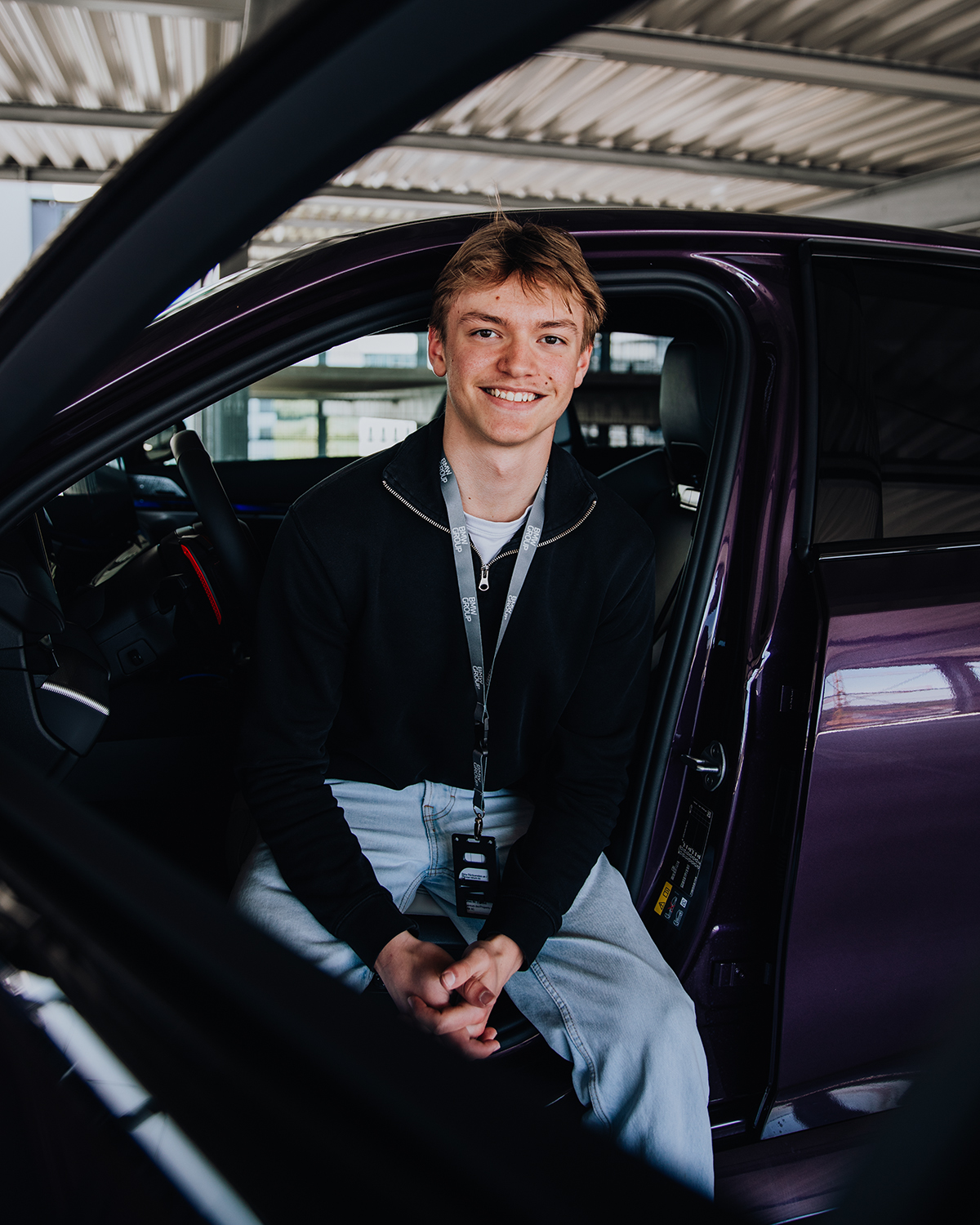 Azubi Tobias auf dem Fahrersitz eines BMW M5 in Lila