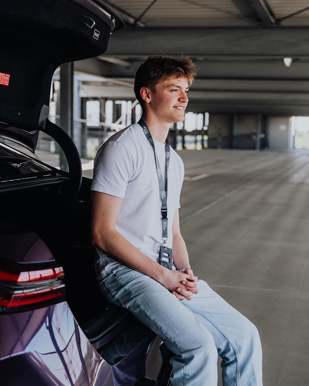 Azubi Tobias sitzt auf der Kofferraum-Laderampe eines BMW M5