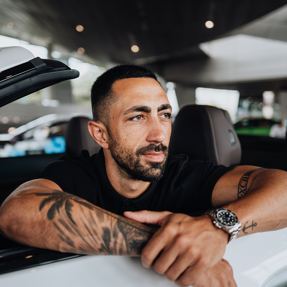 Der BMW Mitarbeiter sitzt im Cabrio und lehnt sich über die Türe.