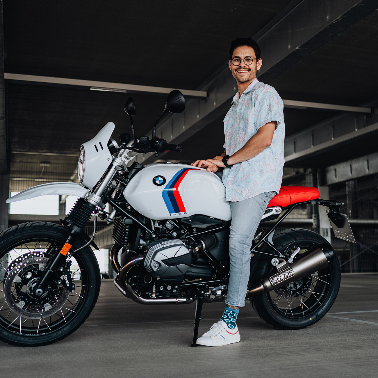 BMW Mitarbeiter sitzt auf einem BMW Motorrad in einem Parkhaus.