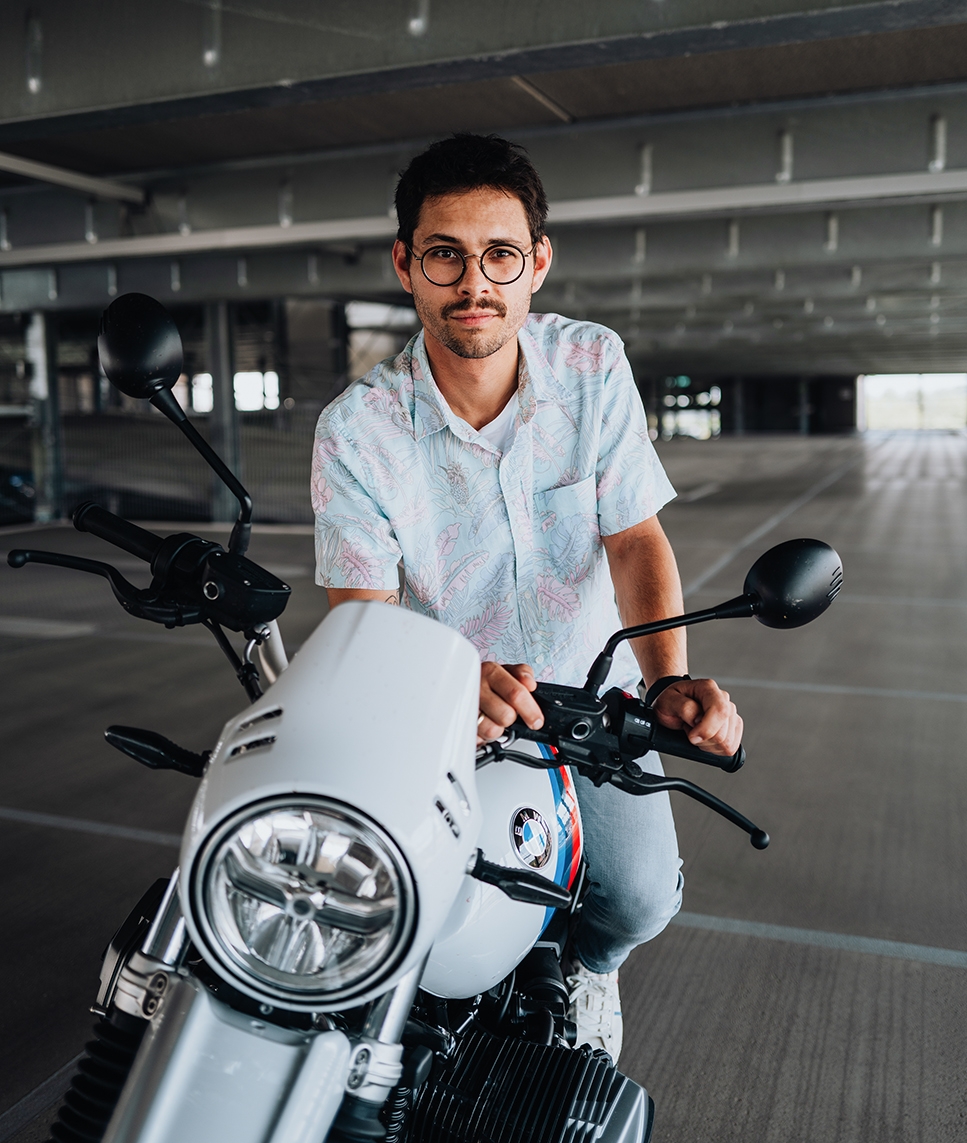 BMW Mitarbeiter sitzt auf einem BMW Motorrad und schaut in die Kamera.