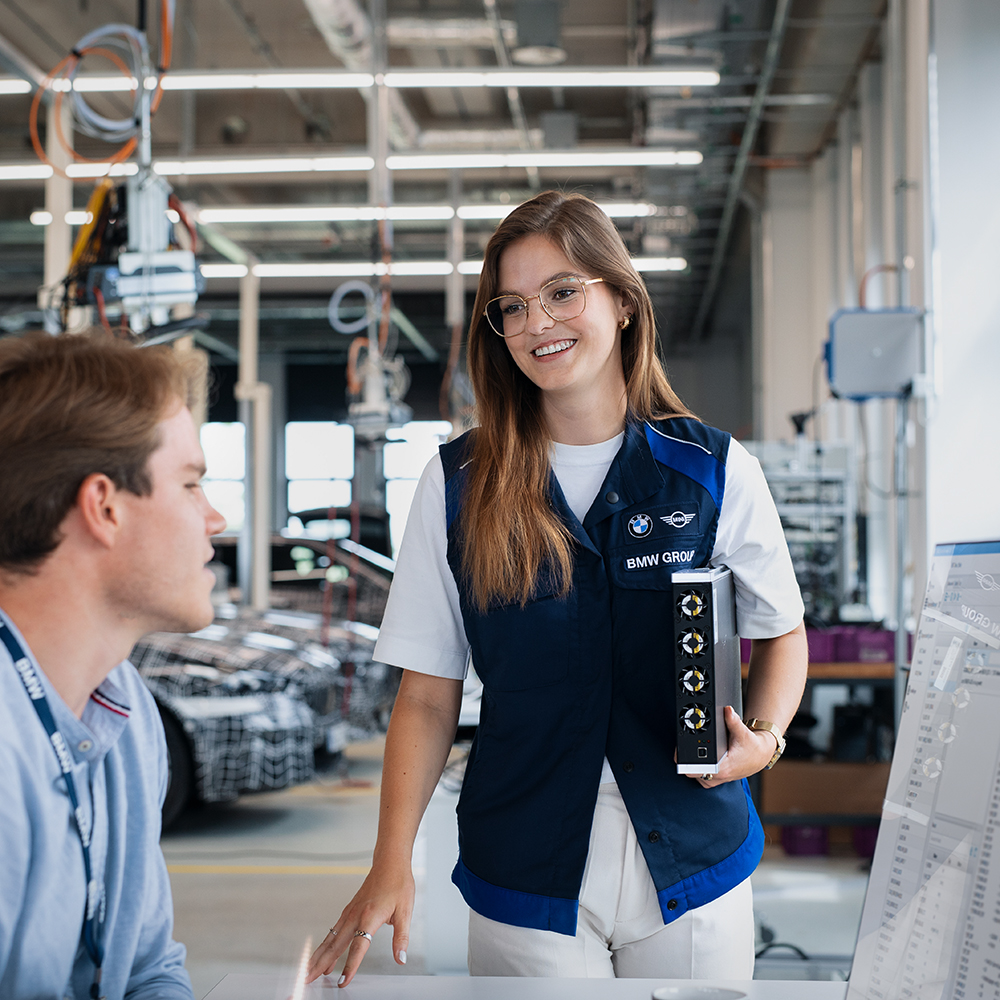 The image shows a men and a women in a meeting talking behind a laptop.