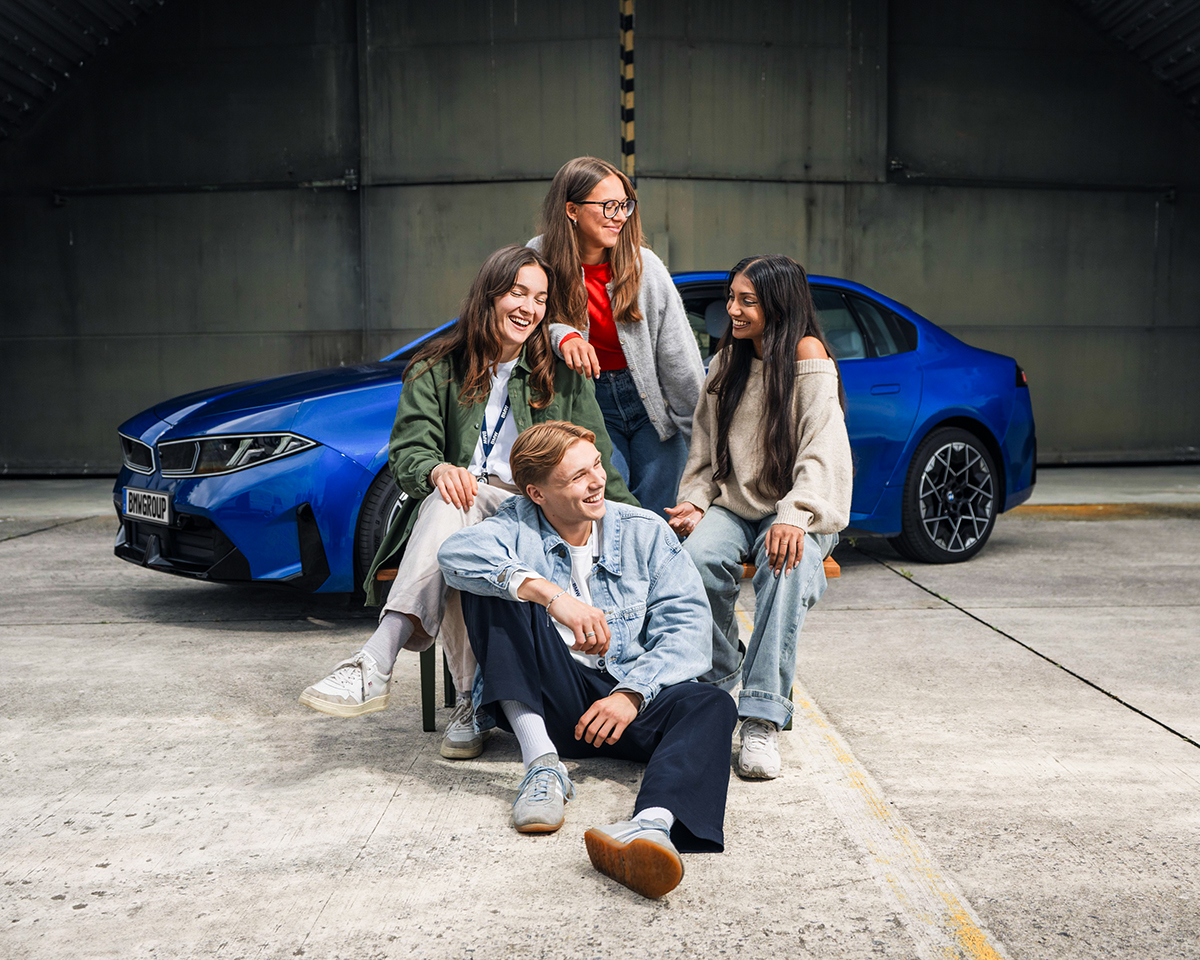 Four students posing as a group in front of a BMW i3