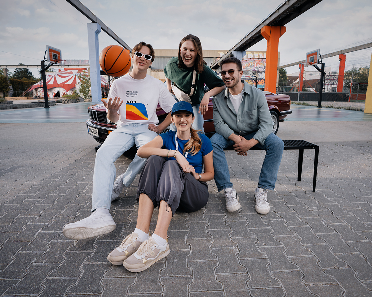 A group of four friends enjoying basketball outdoors with a vintage BMW in the background.