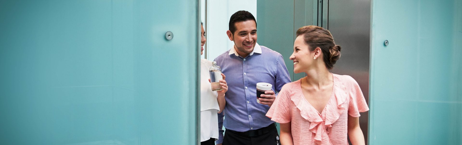 Three colleagues having a conversation while walking through their office.