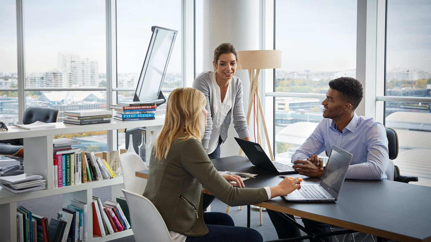 Three BMW colleagues are having a conversation in the office with big windows.